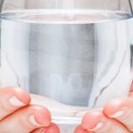 Frauenhände, die ein Glas Wasser halten